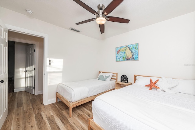 bedroom featuring baseboards, a ceiling fan, visible vents, and light wood-style floors
