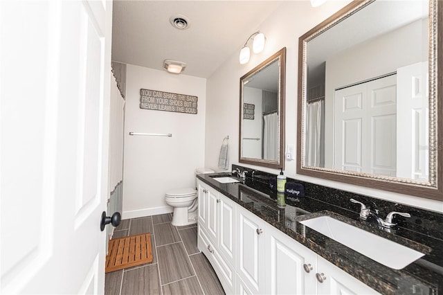 bathroom with double vanity, visible vents, toilet, and a sink