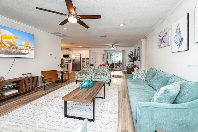 living area featuring a ceiling fan, crown molding, a textured ceiling, and light wood-style flooring