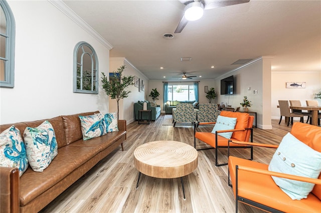 living area with light wood-type flooring, ceiling fan, baseboards, ornamental molding, and visible vents