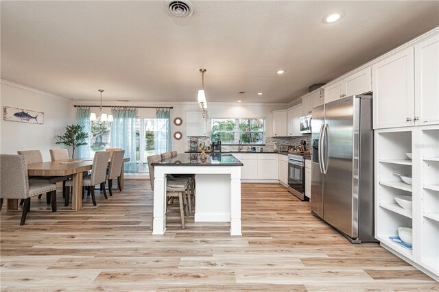 kitchen featuring stainless steel appliances, dark countertops, visible vents, crown molding, and light wood-style flooring