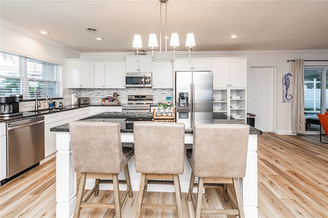 kitchen with crown molding, a center island, a sink, a wealth of natural light, and appliances with stainless steel finishes