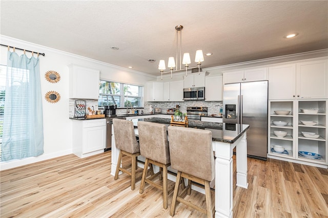 kitchen with light wood-style flooring, ornamental molding, appliances with stainless steel finishes, and tasteful backsplash