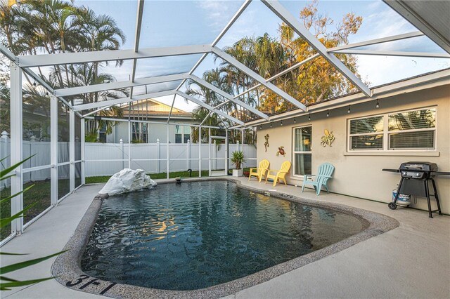 view of swimming pool featuring a fenced backyard, a fenced in pool, glass enclosure, and a patio