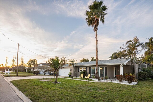 view of front of home featuring stucco siding, a lawn, driveway, and a garage