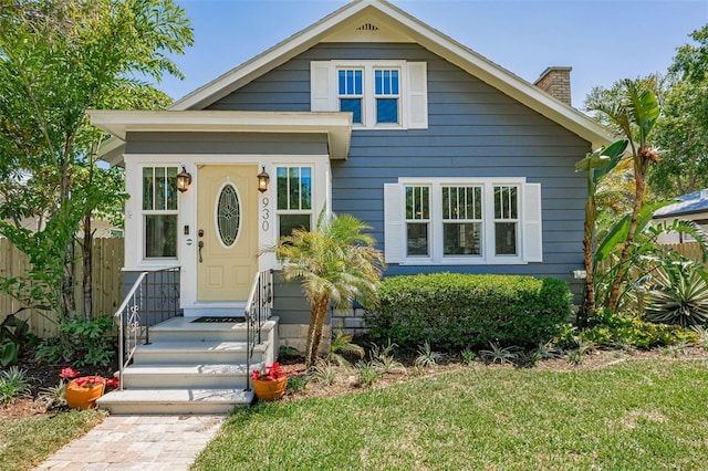 bungalow-style house featuring fence, a front lawn, and a chimney