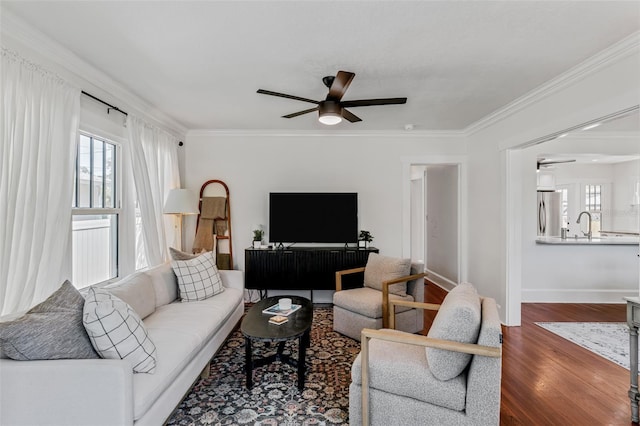 living area with crown molding, wood finished floors, a ceiling fan, and plenty of natural light