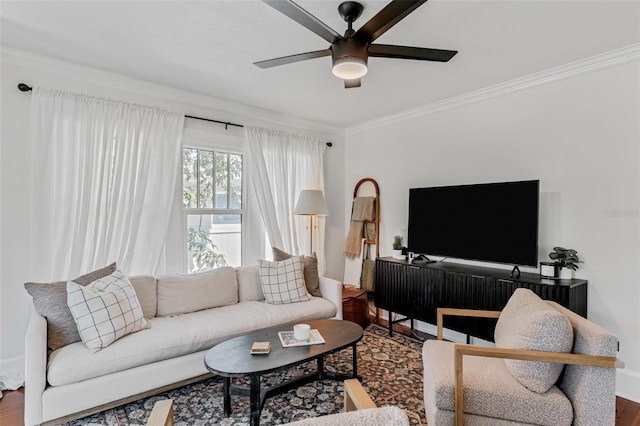 living room featuring a ceiling fan, baseboards, crown molding, and wood finished floors