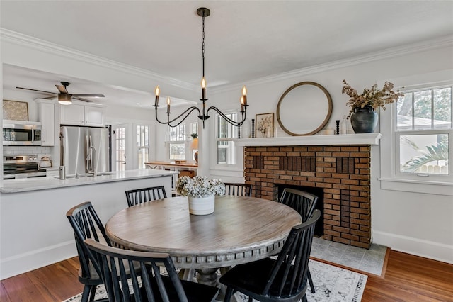 dining room featuring wood finished floors, a ceiling fan, baseboards, and ornamental molding