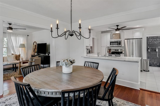dining area featuring ornamental molding, baseboards, a ceiling fan, and light wood finished floors