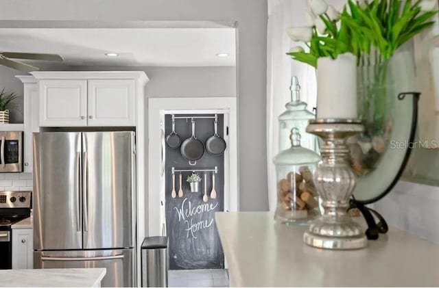kitchen with light countertops, a ceiling fan, decorative backsplash, appliances with stainless steel finishes, and white cabinetry