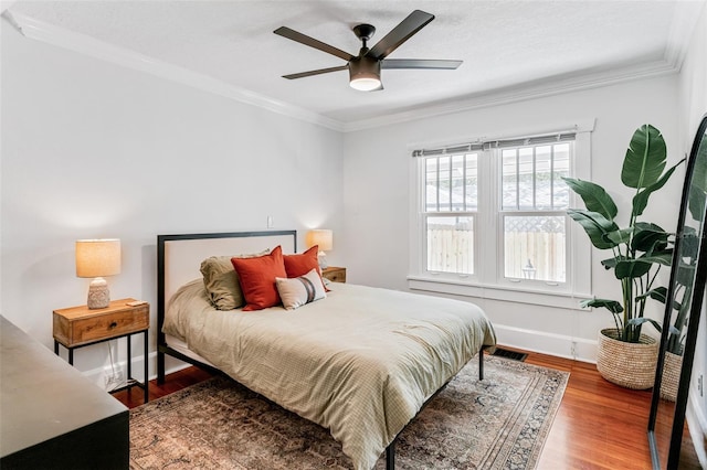 bedroom with a ceiling fan, crown molding, wood finished floors, and visible vents