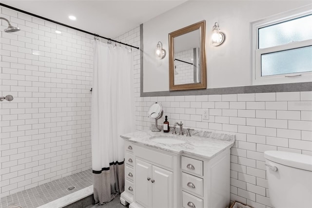 bathroom featuring vanity, tile walls, a wainscoted wall, toilet, and tiled shower