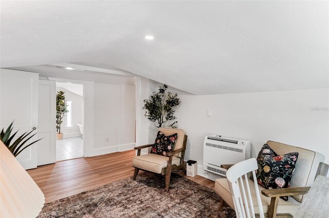 living area featuring recessed lighting, vaulted ceiling, light wood-style flooring, and heating unit