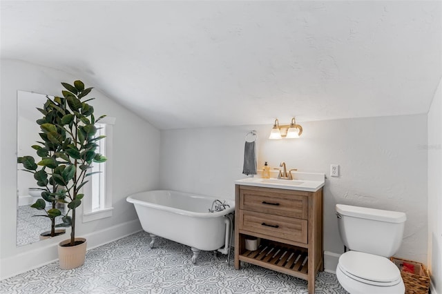 bathroom featuring a freestanding bath, vaulted ceiling, toilet, vanity, and baseboards