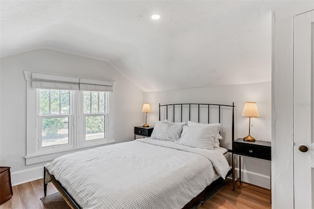 bedroom with lofted ceiling, wood finished floors, and baseboards