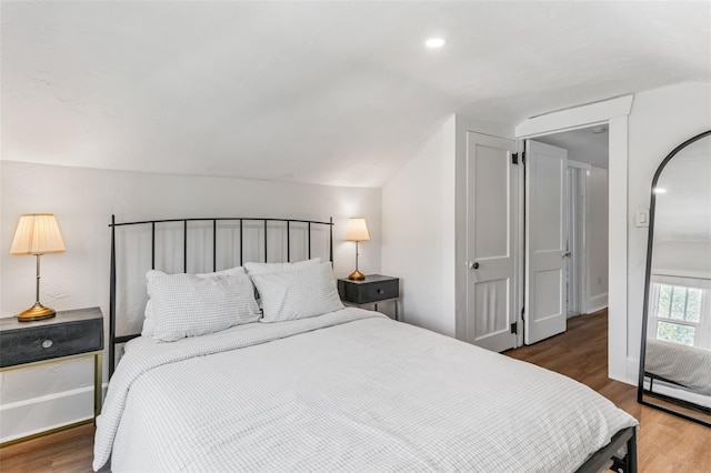 bedroom with lofted ceiling and wood finished floors