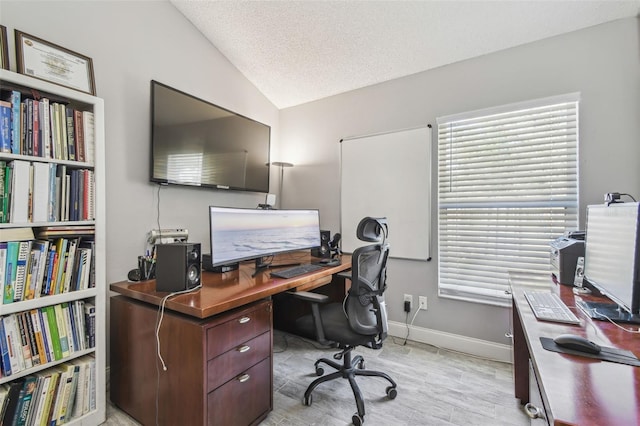 home office with lofted ceiling, baseboards, and a textured ceiling