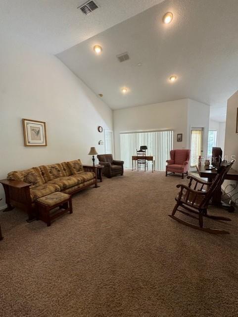 living room with carpet floors, recessed lighting, visible vents, and high vaulted ceiling