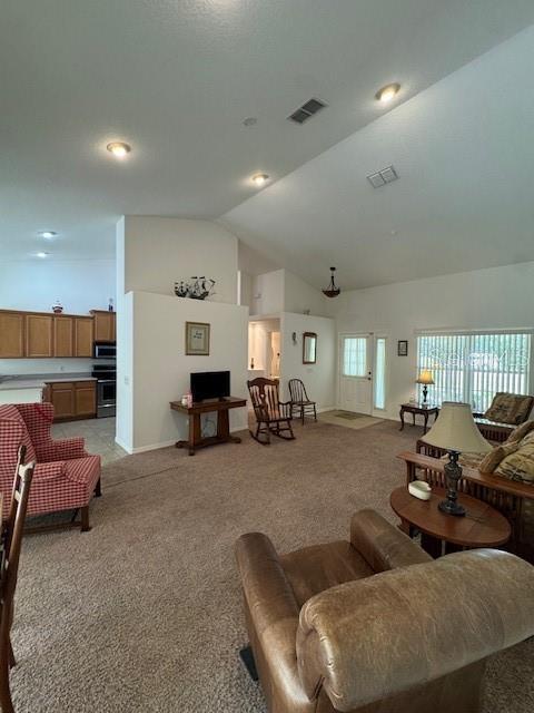 living room featuring visible vents, baseboards, light colored carpet, and vaulted ceiling