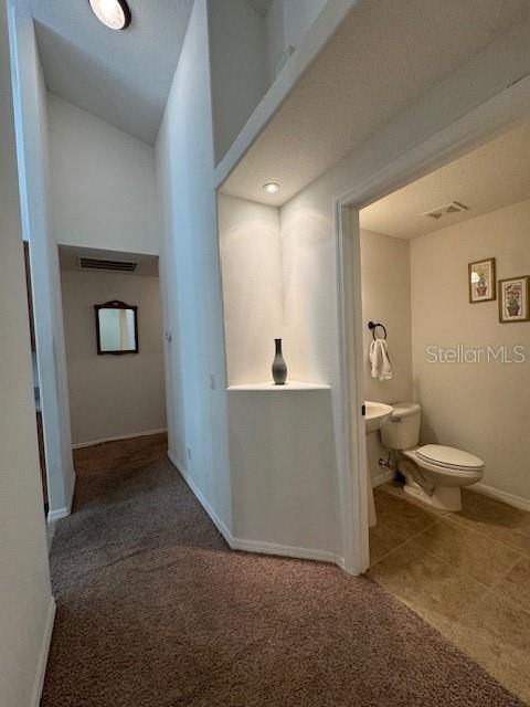 hallway featuring carpet flooring, baseboards, and visible vents