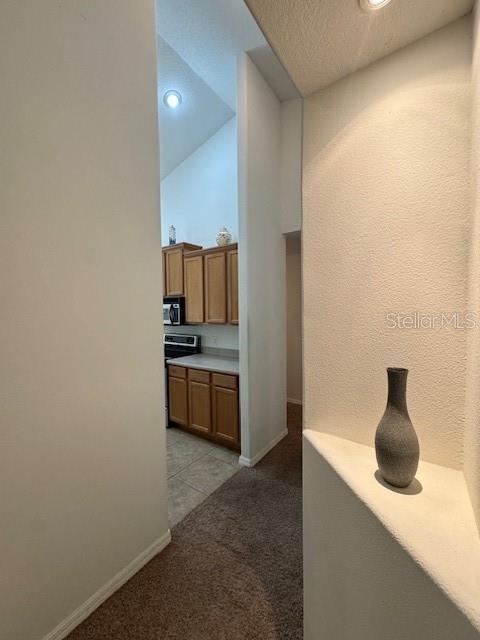 corridor featuring baseboards, vaulted ceiling, recessed lighting, and light colored carpet