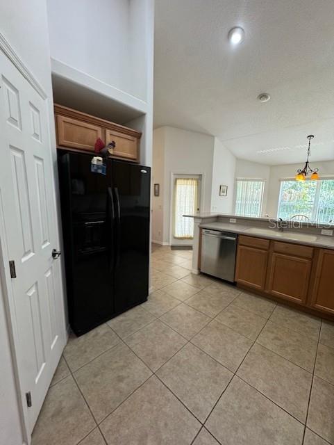 kitchen featuring a sink, black refrigerator with ice dispenser, brown cabinetry, light tile patterned floors, and stainless steel dishwasher
