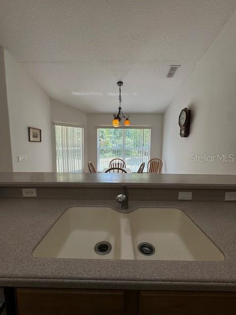 room details with a sink, pendant lighting, a textured ceiling, and visible vents