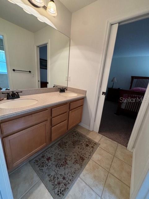 bathroom with double vanity, tile patterned floors, a sink, and ensuite bath