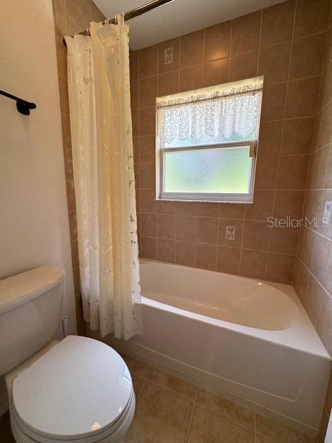 bathroom featuring tile patterned floors, toilet, and shower / tub combo