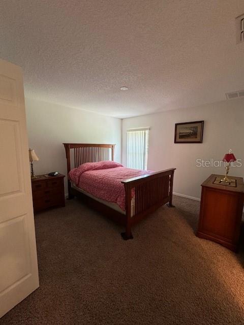 bedroom with carpet floors and a textured ceiling
