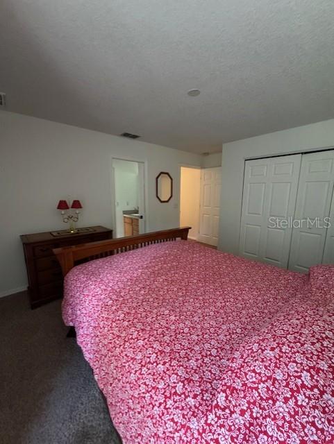 bedroom featuring a closet, baseboards, visible vents, and dark colored carpet