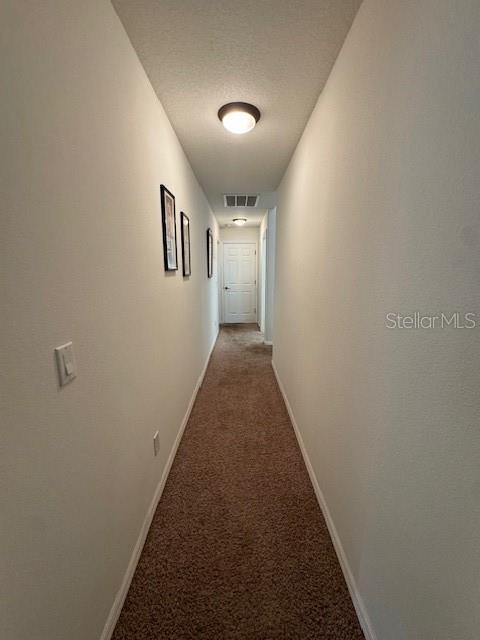 hallway with carpet flooring, baseboards, and visible vents