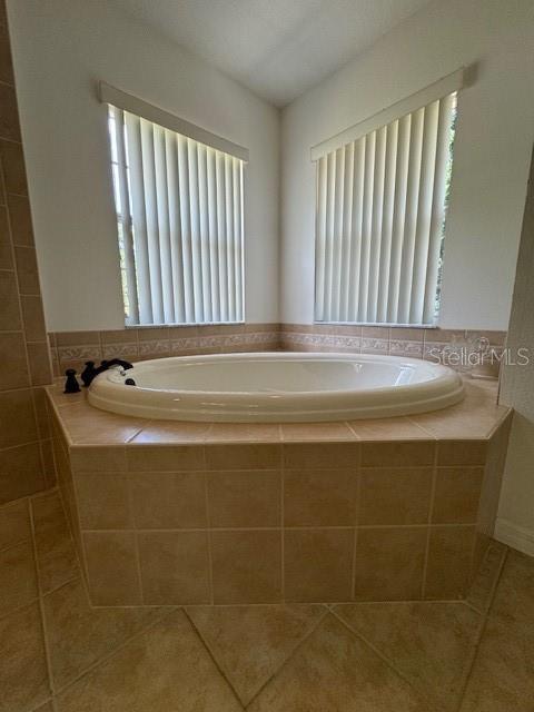 bathroom with tile patterned floors and a bath