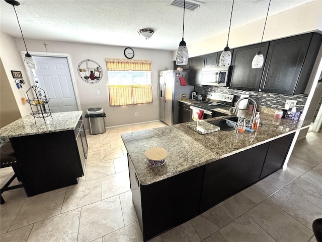 13924 Pathfinder Dr, Tampa, FL 33625 - kitchen with appliances with stainless steel finishes, dark cabinets, decorative backsplash, light stone countertops, and a textured ceiling