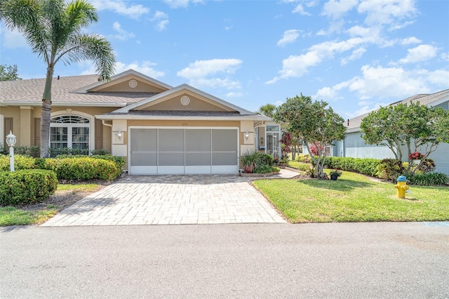 ranch-style home featuring a garage, stucco siding, driveway, and a front yard