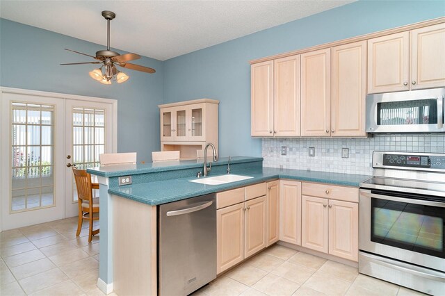 kitchen with a ceiling fan, backsplash, appliances with stainless steel finishes, a sink, and light tile patterned flooring