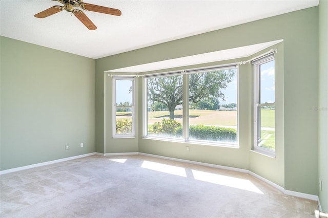 spare room featuring a ceiling fan, baseboards, and light colored carpet