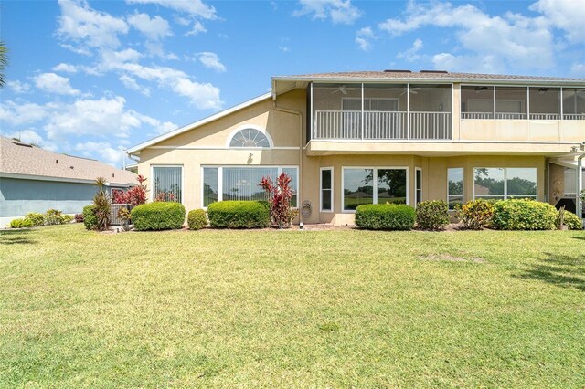 rear view of property featuring a sunroom, stucco siding, and a yard