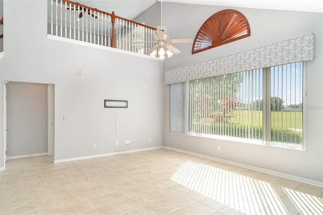 tiled empty room with baseboards, high vaulted ceiling, and ceiling fan