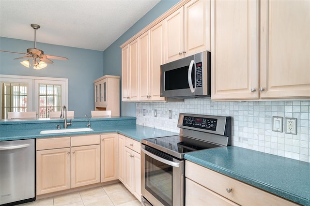 kitchen with ceiling fan, a textured ceiling, a sink, appliances with stainless steel finishes, and backsplash