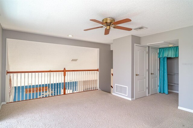 spare room featuring carpet floors, ceiling fan, and visible vents