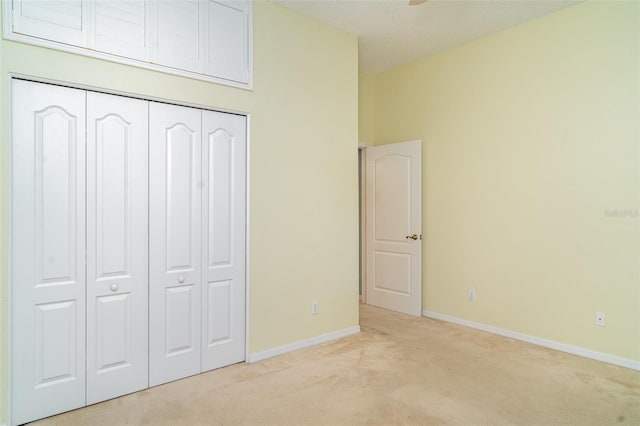 unfurnished bedroom featuring baseboards, light carpet, and a closet