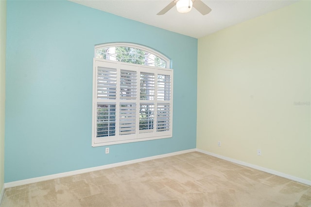 unfurnished room with baseboards, a ceiling fan, and light colored carpet