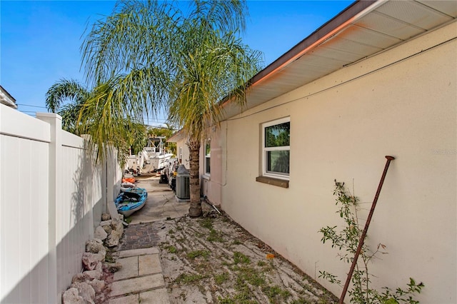 view of home's exterior with fence, stucco siding, and central AC unit