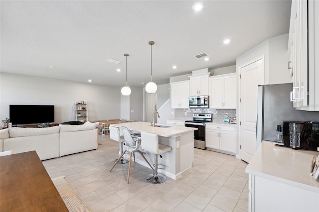 kitchen with decorative backsplash, a breakfast bar area, light countertops, open floor plan, and stainless steel appliances