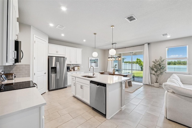 kitchen featuring visible vents, open floor plan, a sink, appliances with stainless steel finishes, and backsplash