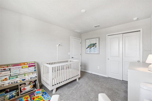 carpeted bedroom featuring visible vents, baseboards, a nursery area, and a closet