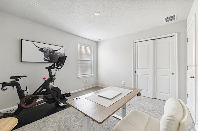 exercise room featuring baseboards, carpet, a textured ceiling, and visible vents
