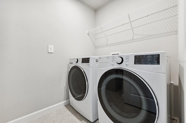 washroom featuring baseboards, laundry area, washing machine and dryer, and light tile patterned flooring
